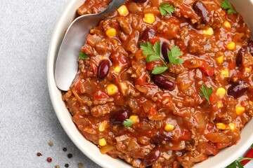 Delicious chili con carne served on light gray table, top view
