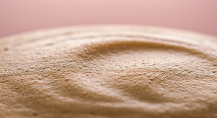 A close-up of a beige textured surface with a pinkish background