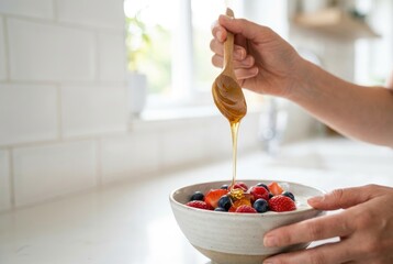 Delicious fruit bowl topped with honey in a kitchen during breakfast time with fresh berries and yogurt