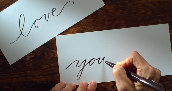 Slow Motion Shot Of Hand Writing The Words Love Yourself With A Pen On White Paper At 1000 Fps. Concept Of Self Care, Mindfulness, Personal Growth, Calligraphy And Emotional Expression