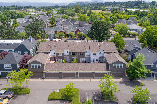 Aerial view of neat rows of townhouses with varied rooflines and lush green trees creating a serene suburban landscape, Fairview, Oregon, United States.