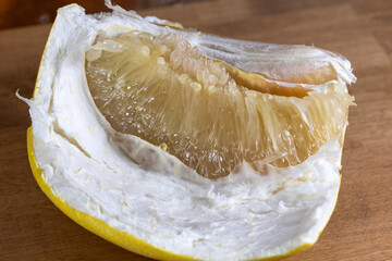 A peeled grapefruit slice. An orange slice on the table.