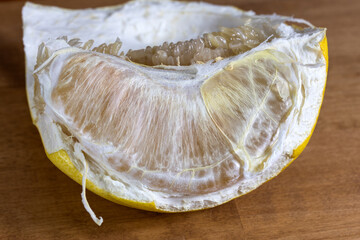 A peeled grapefruit slice. An orange slice on the table.