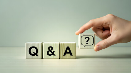 Q&A wooden blocks, a hand placing the 'A' block with a question mark symbol