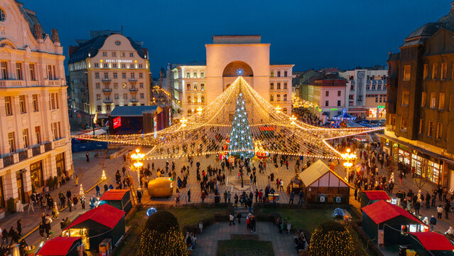 Aerial view of Christmas lights twinkle over Victory Square, illuminating the Metropolitan Cathedral and the bustling Christmas market below, Timisoara, Timis, Romania.