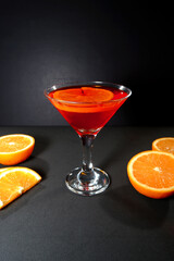 Vibrant orange cocktail juice glass with fresh citrus on black background closeup view
