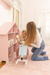 Mother and toddler baby playing on the rocking bike in the kindergarten
