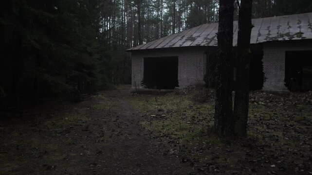 War in Ukraine destroyed building dim forest garage at dusk, moss covered path leads to vacant concrete shelter, silent openings framed by tall pines and damp leaf litter underfoot, urban