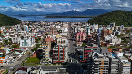 Drone footage of the coastal city of Guaratuba, Paran&aacute;, on a sunny morning, blending the blue sky with clouds, the beach, and the city.