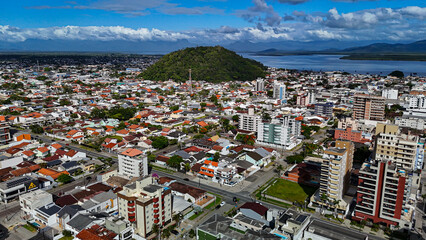 Drone footage of the coastal city of Guaratuba, Paran&aacute;, on a sunny morning, blending the blue sky with clouds, the beach, and the city.
