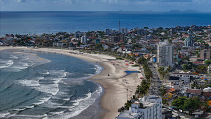 Drone footage of the coastal city of Guaratuba, Paran&aacute;, on a sunny morning, blending the blue sky with clouds, the beach, and the city.