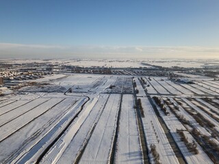 sun shines on heavy snowfall in the Netherlands covers farmland fields in polder. Drone footage of rural winter weather snow scene beautiful landscape  