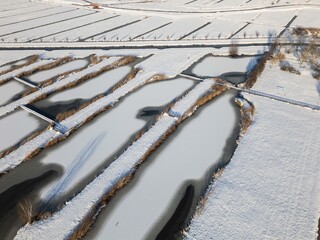 sun shines on heavy snowfall in the Netherlands covers farmland fields in polder. Drone footage of rural winter weather snow scene beautiful landscape  
