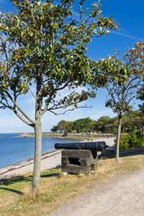 Obraz premium Historic cannon on a wooden carriage by the water at Landskrona Citadel coastal park in Sweden