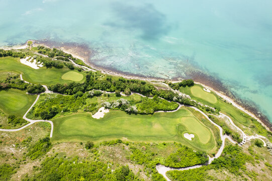 Aerial view of the vibrant green golf course contrasting with the turquoise sea at Thracian Cliffs Golf & Beach Resort, Bozhurets, Bulgaria.