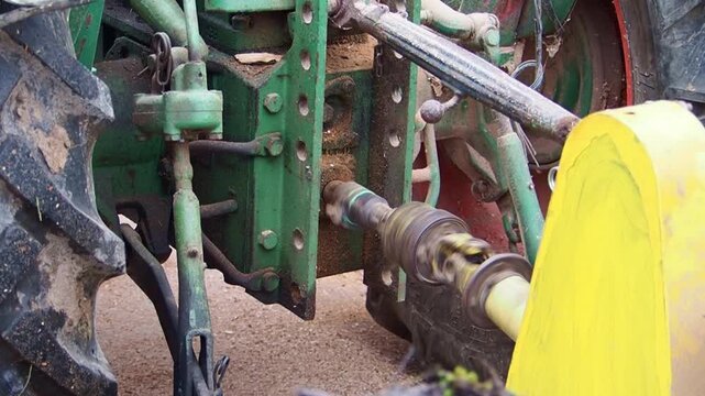 A close-up view of the power take-off shaft of an old tractor in operation. The rotating mechanical component drives attached equipment, highlighting traditional agricultural machinery and functionali