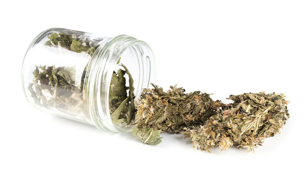 Dried medicinal herbs in glass jar isolated on white