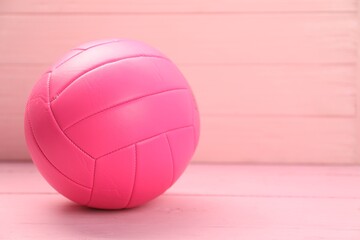 One volleyball ball on pink wooden table, closeup. Space for text