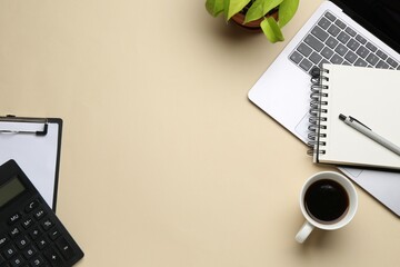 Office workplace. Stationery, laptop, coffee and floral decor on beige background, flat lay. Space...