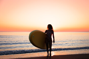 Young woman standing on beach with paddle sup boards during summer vacation