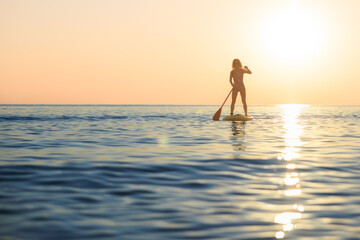 Young woman walking on stand up paddle sup boards by the sea during summer vacation