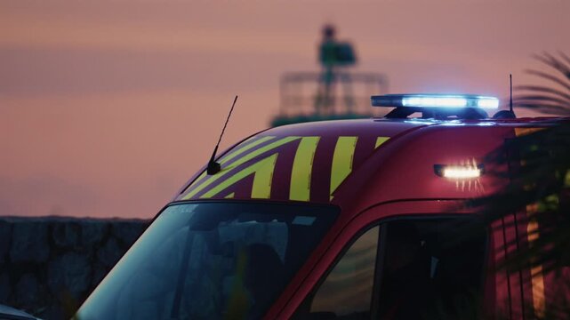 Side view of a red ambulance moving through Antibes during dusk