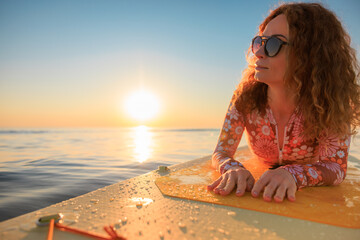 Young woman walking on stand up paddle sup boards by the sea during summer vacation