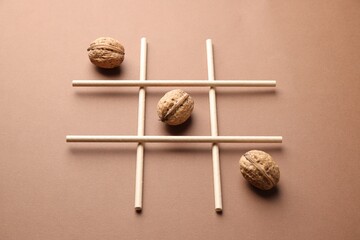 Tic tac toe game made with walnuts on beige background