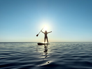 Young woman walking on stand up paddle sup boards by the sea during summer vacation