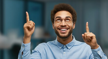 Man with glasses smiling and pointing upward with enthusiastic expression