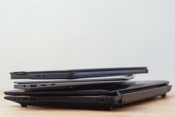 Close up view of stacked laptops on wooden surface. Concept of modern technology, corporate work, productivity and professional equipment.