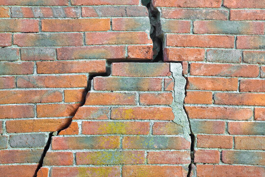 Dangerous old exposed cracked brick wall due to structural foundation failure, soil subsidence, corrosion and deterioration of building materials, earthquake