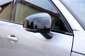 A modern white car's glossy black side-view mirror with an integrated LED turn signal. This close-up highlights the vehicle's sleek, aerodynamic design and reflective surface.