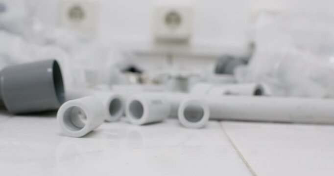 Polypropylene coupling rolls across workbench past fittings and sleeves. Shallow focus shows rolling ring on smooth surface while background pipes stay calm slow motion