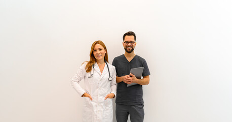 Portrait of professional doctors with laptop and stethoscope standing confidently against white background