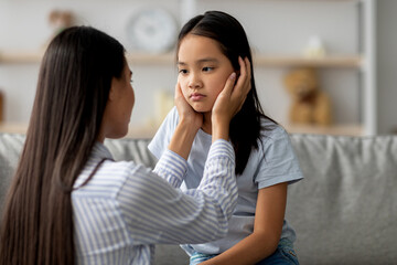Childhood problems concept. Young mother comforting her sad offended daughter after quarrel at...