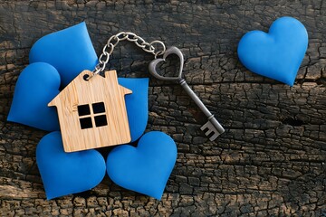 Wooden house keychain with blue hearts and key on wooden background