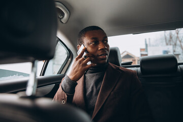 Young black man talking on mobile phone in car backseat © anatoliycherkas