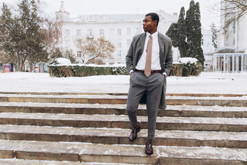 Professional man standing on snowy urban stairs