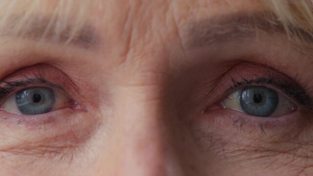 Extreme closeup female blue eyes with wrinkles looking at camera unrecognizable old Caucasian woman retired senior grandmother with wrinkled face look gaze eyesight vision cataract health medicine