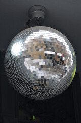 Silver disco mirror ball hanging on the wall. Light party supplier .