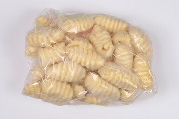 A transparent plastic bag filled with frozen gnocchi isolated on a plain white background
