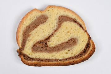 A top down view of a single slice of homemade walnut roll showing the spiral pattern of sweet nut filling on a plain white background