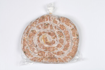 A spiral shaped frozen homemade sausage packed in a transparent plastic bag on a white background