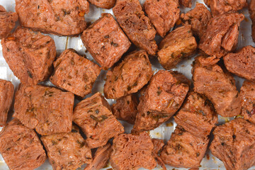 A top down macro view of cooked and seasoned vegan meat chunks made from soy protein showing fibrous texture and herbs
