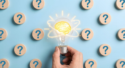 hand holding lightbulb with brain and question marks on blue background