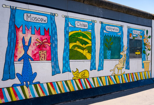 Colorful mural on the Berlin Wall depicting playful illustrations of windows labeled Moscow, China, Everywhere, and Berlin