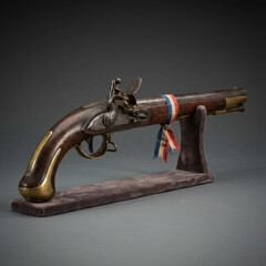 Antique flintlock pistol on display stand with tricolor ribbon