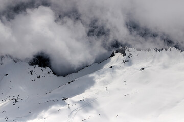 Dramatic winter landscape of Zugspitze mountain ridge covered in snow and heavy clouds.