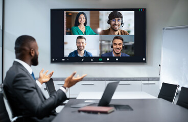 A group of four people joins a video call while one participant talks from a conference room. The...
